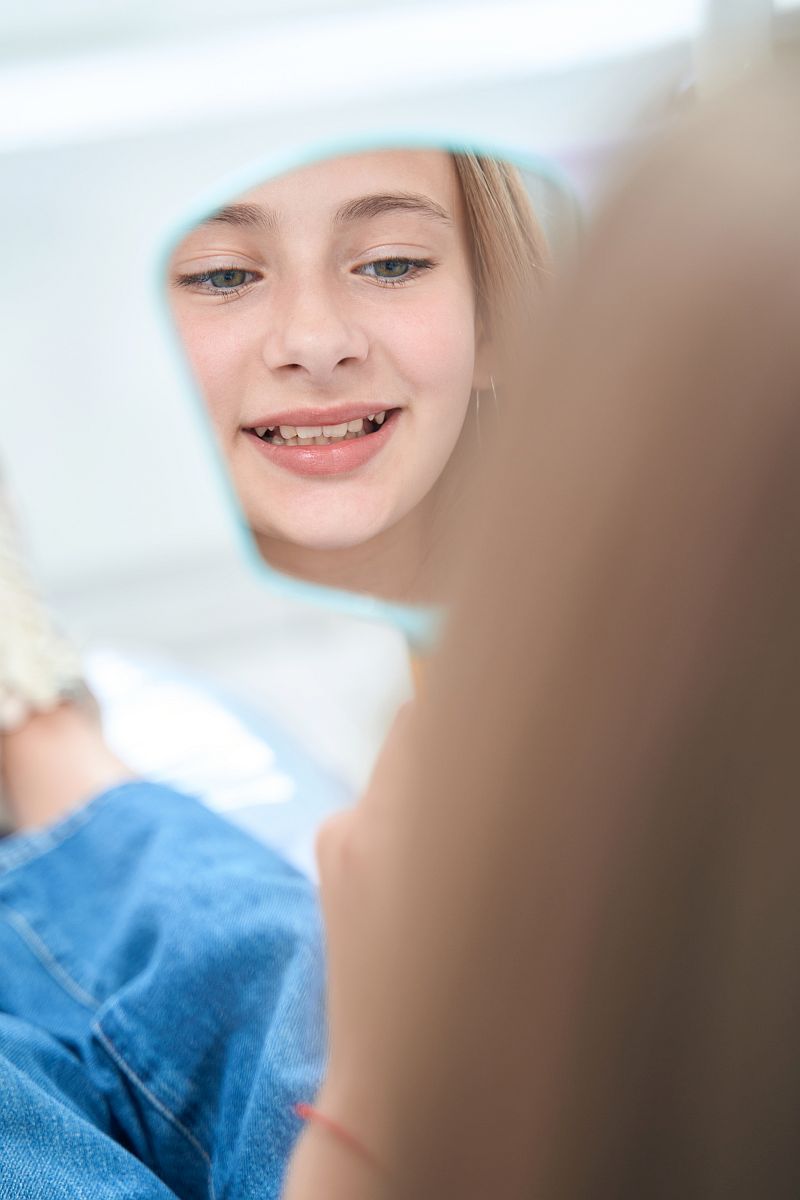 Focused calm teenage girl examining her teeth